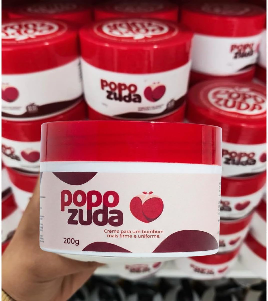 Mão segurando o pote Popozuda diante de outros potes